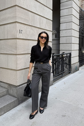 a lady in a black shirt and a pair of grey wide leg pants